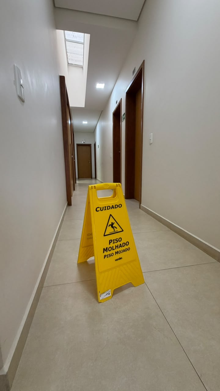 Corredor da Clínica Revita com placa de piso molhado durante a limpeza
